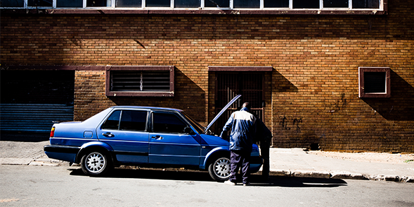 Men working on blue car photo by Marc Steenbeke on Unsplash
