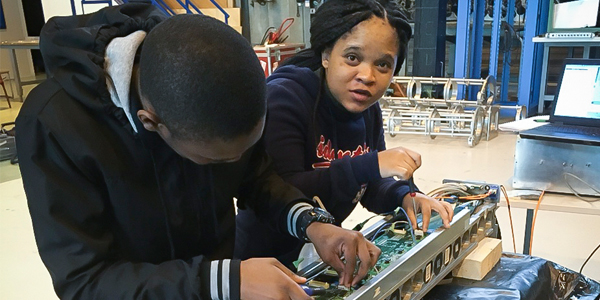 Students of the High Energy Particle Physics group works on a piece of electronic equipment